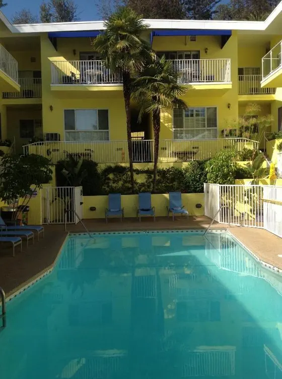 Swimming pool in front of a hotel with chairs and a building