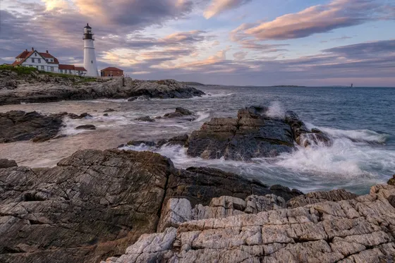 Portland Head Light above a rocky coast at sunset