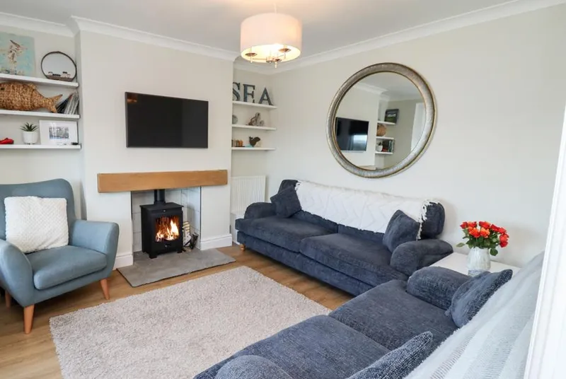 Mariner's Watch living room with lit wood-burning stove and coastal decor