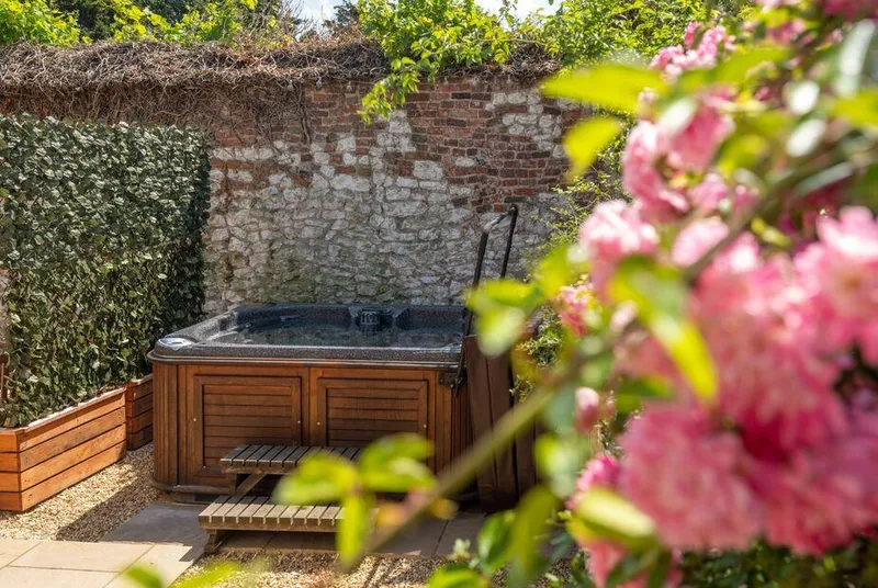 May Cottage Titchwell garden hot tub framed by pink flowers in walled courtyard