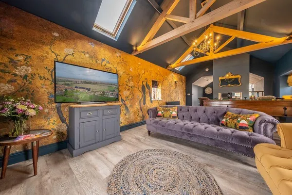 May Cottage Titchwell living room with gold floral wallpaper and exposed beams