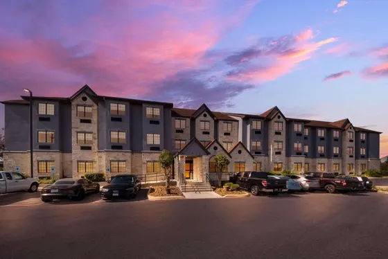 Gray hotel with a stone portico under a purple sunset sky