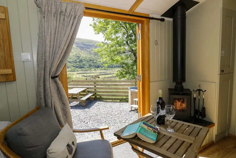 Moelfre Shepherds Hut inside out view with stove and valley beyond
