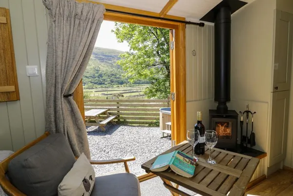Moelfre Shepherds Hut inside out view with stove and valley beyond