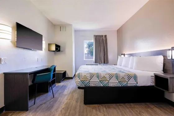 Hotel room with a geometric duvet and a teal desk chair