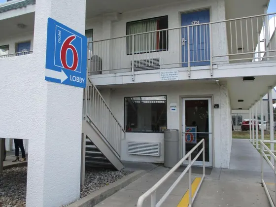 White motel with a blue Motel 6 sign and outdoor stairs