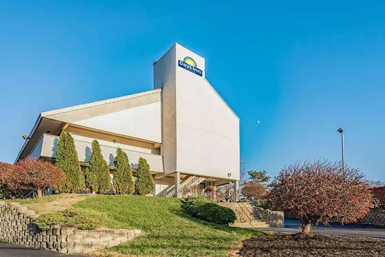 White hotel with a Days Inn sign and evergreen trees