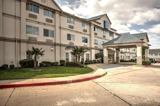 Tan hotel with a covered entrance and small palm trees