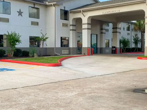 White hotel with a covered entrance, star emblem, and red curb
