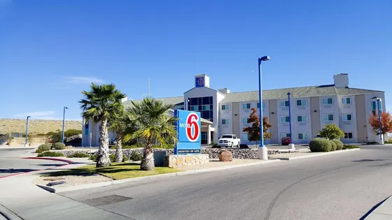 Tan motel with a tall Motel 6 sign and desert hills