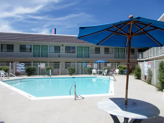Pool with a blue umbrella and a table and chairs