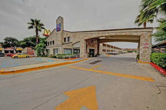 Stone motel with a Motel 6 chimney sign and a driveway arrow
