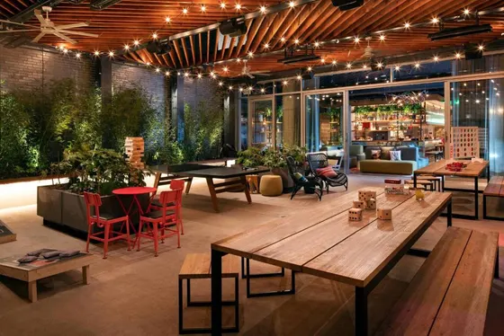 Lounge with wooden tables, string lights, and a ping pong table