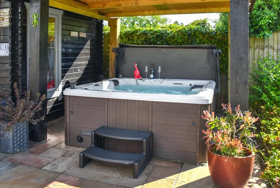 Myrtle Cottage hot tub under wooden pergola in garden