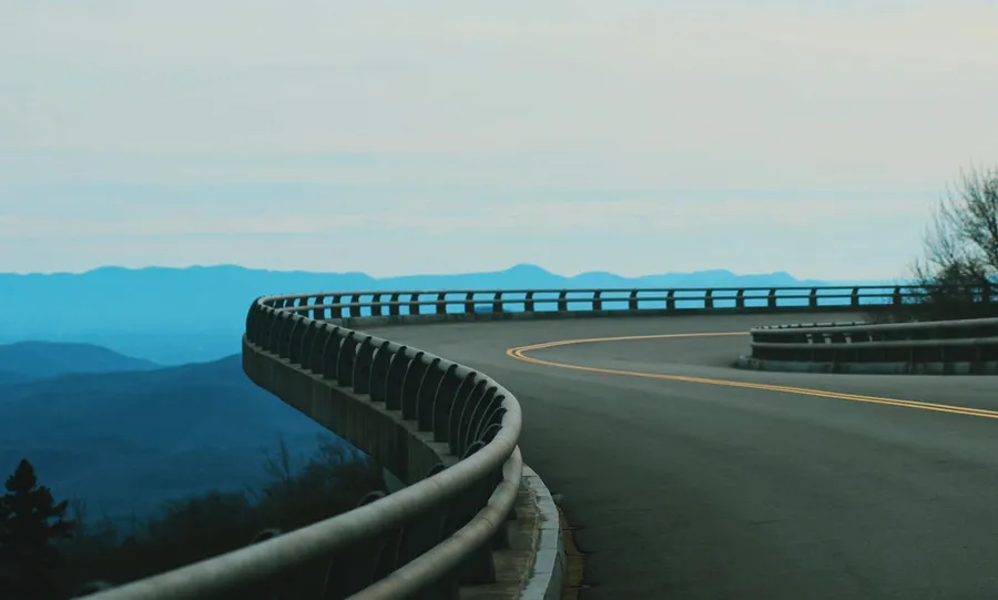 Winding mountain road curving toward hazy blue peaks