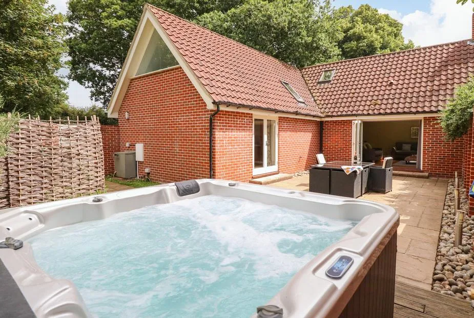 Oak Tree Lodge bubbling hot tub with property and open bifold doors behind