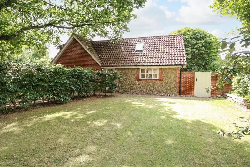 Oak Tree Lodge brick-and-flint lodge with green lawn and mature trees