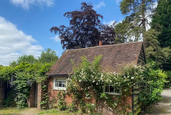 Old Rectory Cottage brick exterior with climbing roses under blue sky
