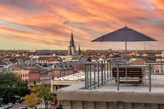 Rooftop terrace with an umbrella overlooking a city skyline at sunset