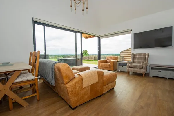 Owl Lodge living room with leather sofa and countryside views through bi-fold doors