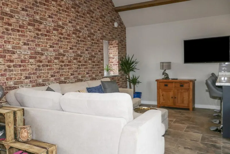 Owl View living room with exposed brick wall and corner sofa