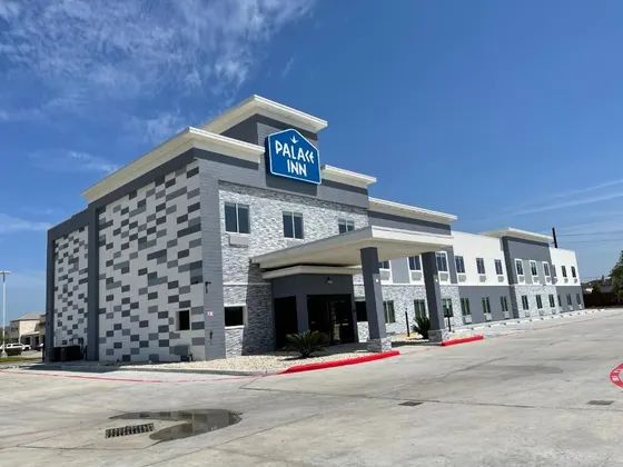 Gray and white hotel with a blue Palace Inn rooftop sign