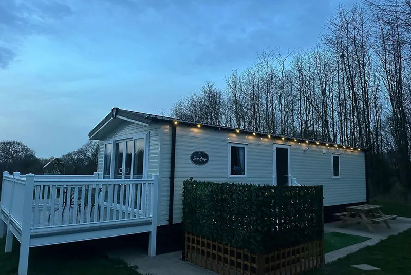 Pheasant Lodge lodge exterior at dusk beside the lit hot tub