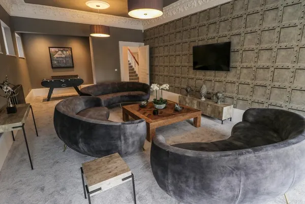 Railway House Gentleman's Lounge with dark curved sofas and industrial textured wall