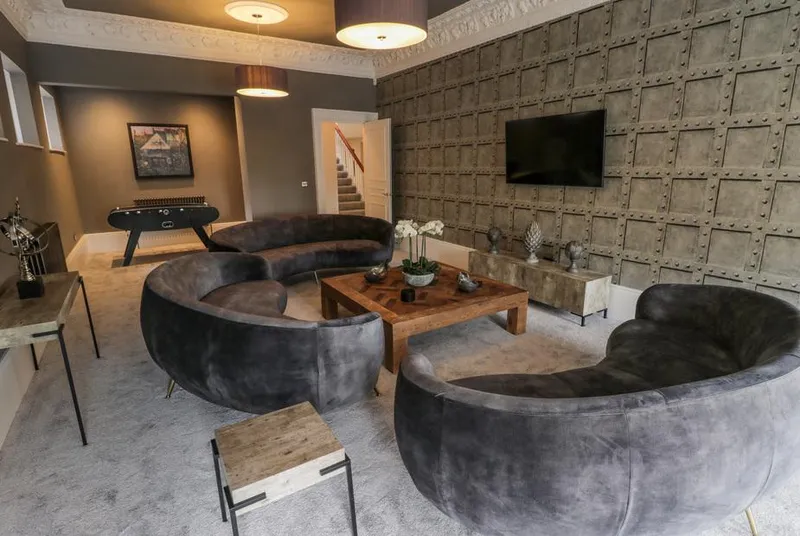 Railway House Gentleman's Lounge with dark curved sofas and industrial textured wall