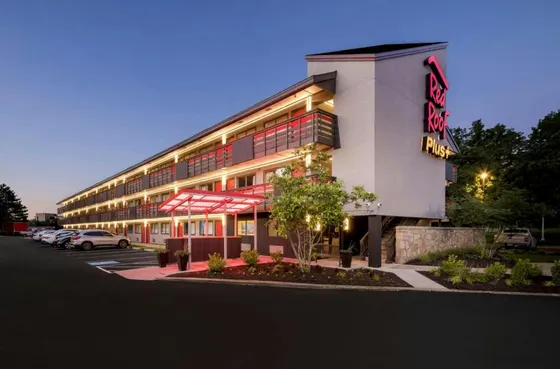 Hotel at dusk with lit red walkways and a roof sign