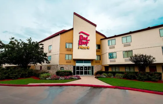 Beige hotel with a Red Roof Plus sign and stone entrance