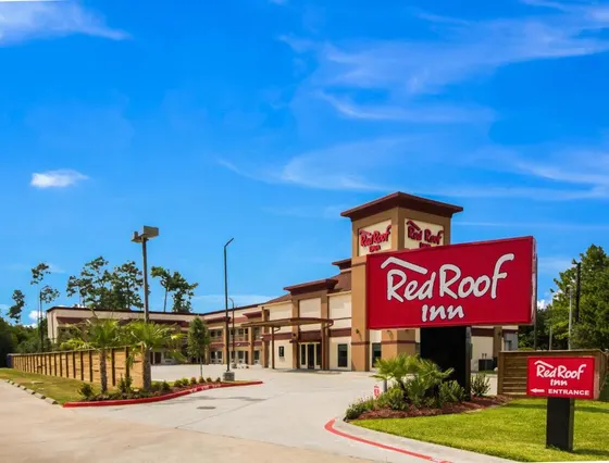 Tall red Red Roof Inn sign beside a beige motel
