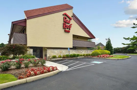 Tan motel with a Red Roof Inn sign and flower beds