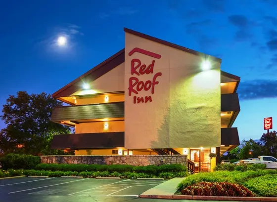 Red Roof Inn facade lit at night beside a parking lot