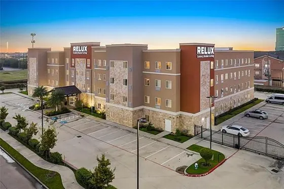 Tan four-story building with Relux Luxury Senior Living signs