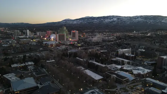 Aerial view of downtown Reno and snow-dusted mountains at dusk