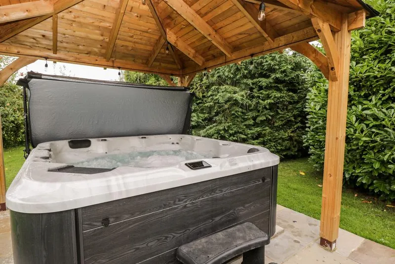Reybridge House hot tub with bubbling water under timber gazebo