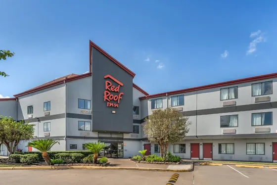 Gray hotel with a Red Roof Inn tower and red doors