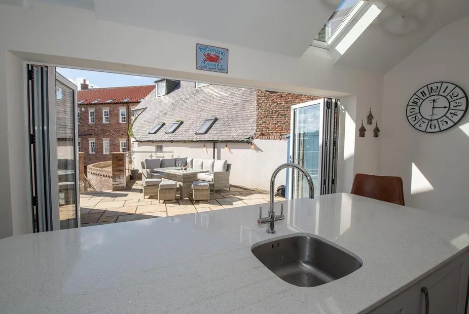 Salt Bay kitchen opening through bifold doors onto patio seating area