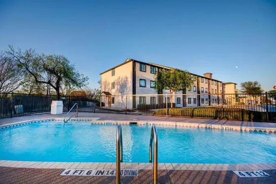 Pool with a ladder and no-diving tiles in front of a hotel