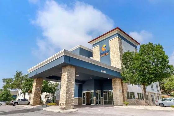Blue and gray hotel with a stone canopy and Comfort Suites sign