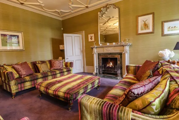 Scale House sitting room with lit fireplace and striped sofas