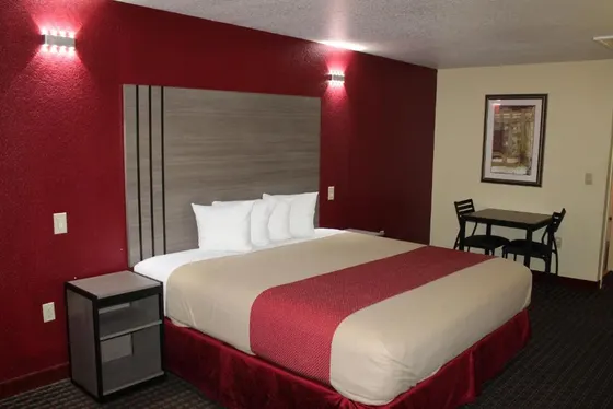 Room with a red wall, tan comforter, and a gray striped headboard