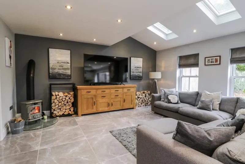 Seamer Manor House living room with lit wood burner, large sofa and skylights