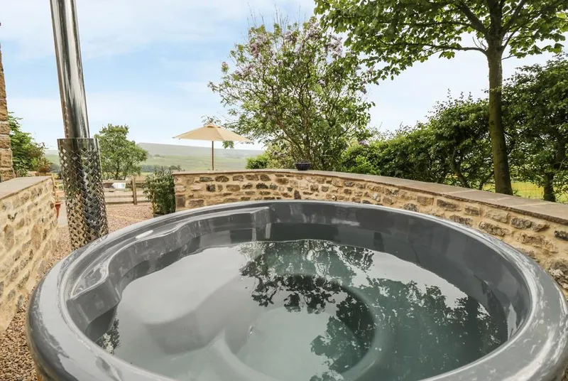 Shawclough Barn hot tub on a patio with hillside backdrop