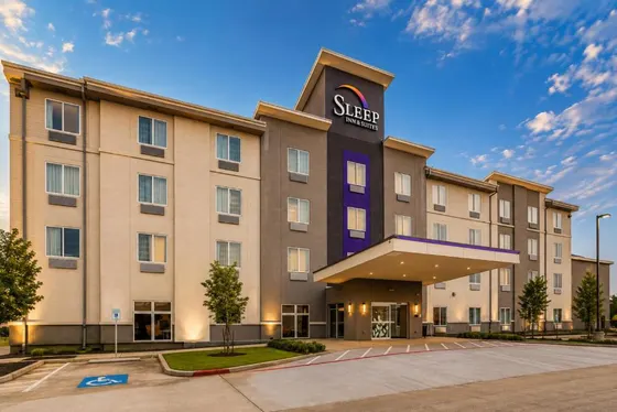 Four-story hotel with a large entrance canopy and parking lot