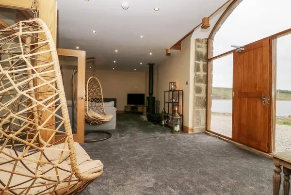 Snave Barn living area with egg chair and barn door to reservoir