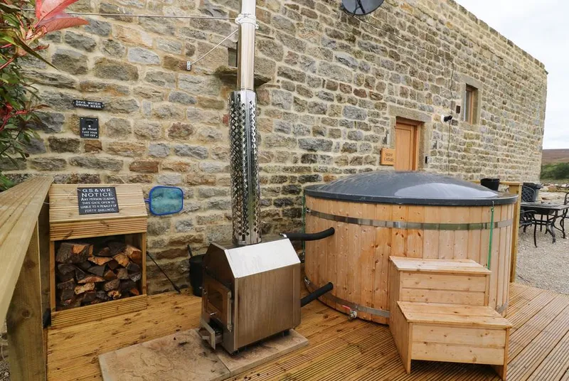Snave Cottage wood-fired hot tub on decking beside stone wall