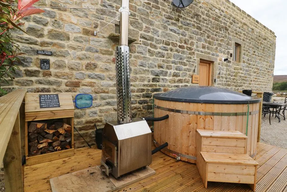 Snave Cottage wood-fired hot tub on decking beside stone wall
