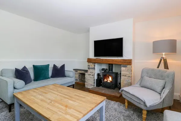 Somerset House living room with lit wood burner in stone fireplace